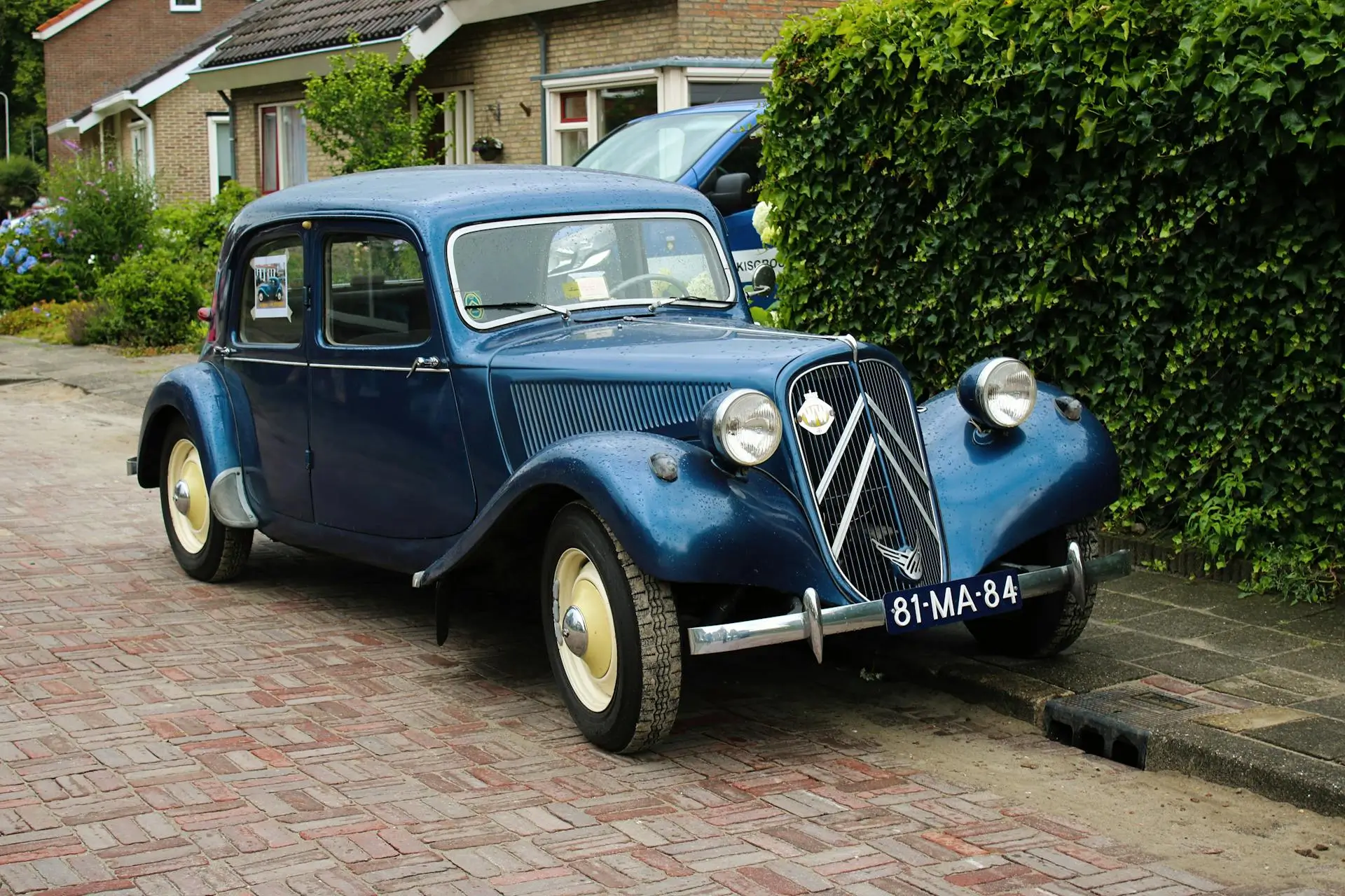 Citroën Traction Avant bleu marine stationnée en quartier résidentiel verdoyant chez johan-prades-garage tarn