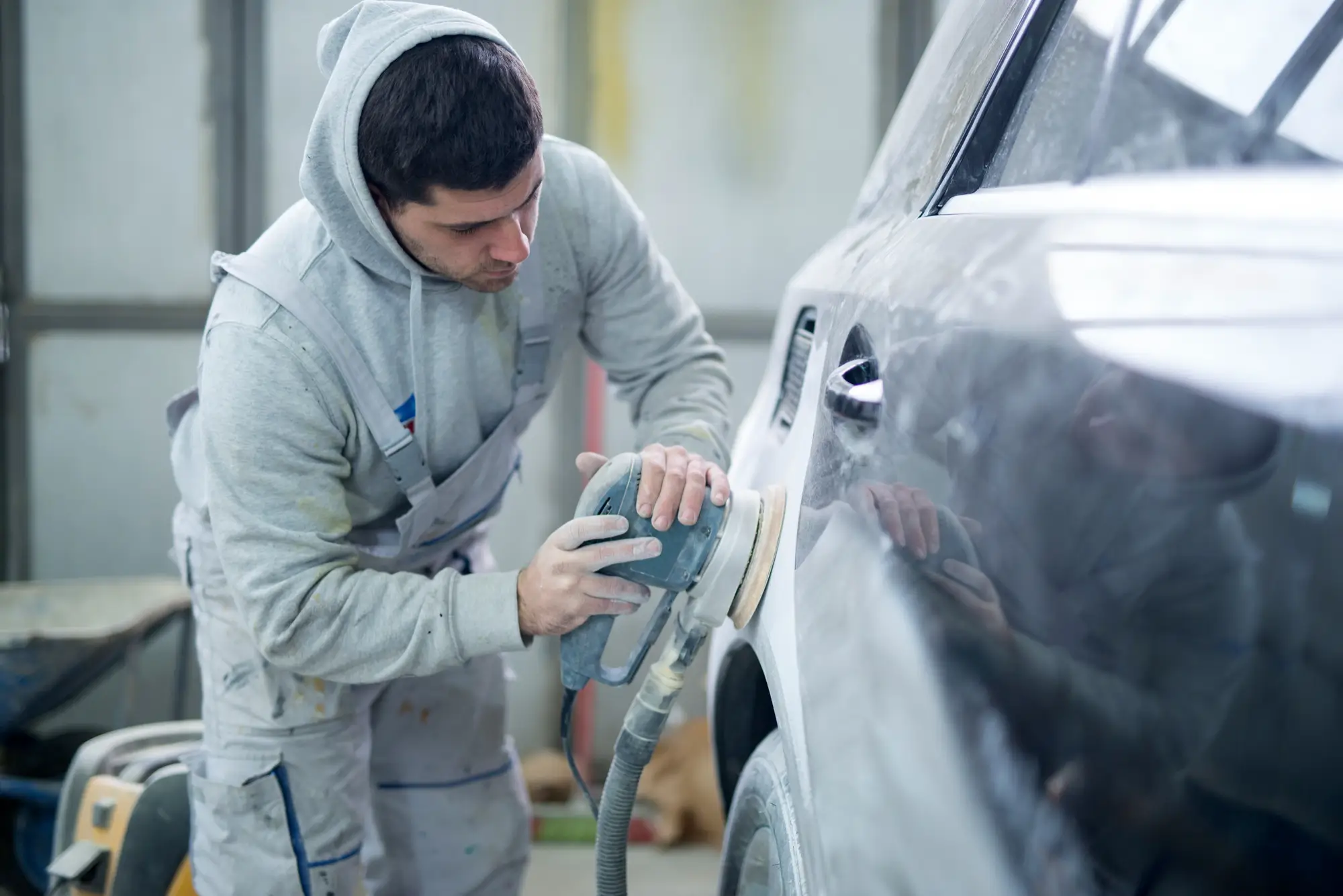Carrossier ponçant une voiture chez johan-prades-garage, atelier de réparation auto dans le tarn